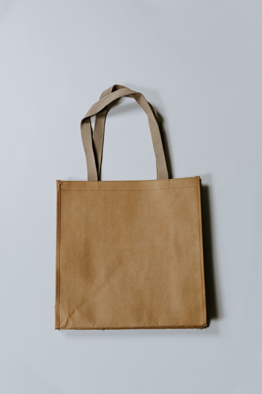 Beige cotton eco tote bag against a grey wall