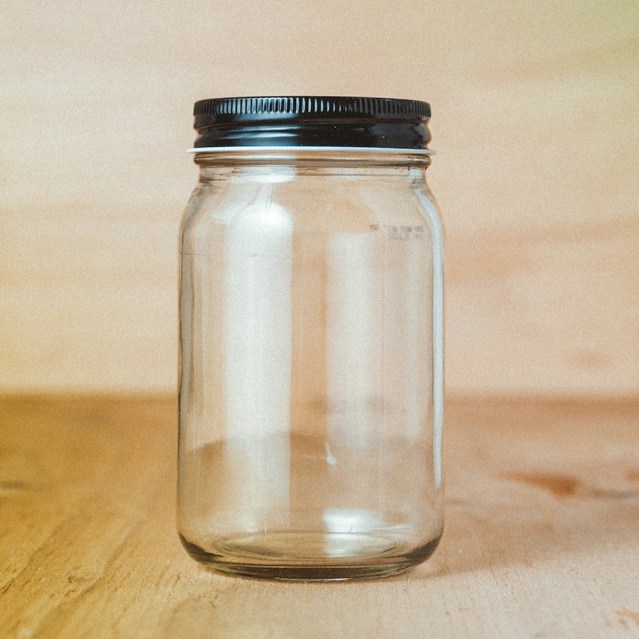 Empty glass jar with a black metal lid on wood