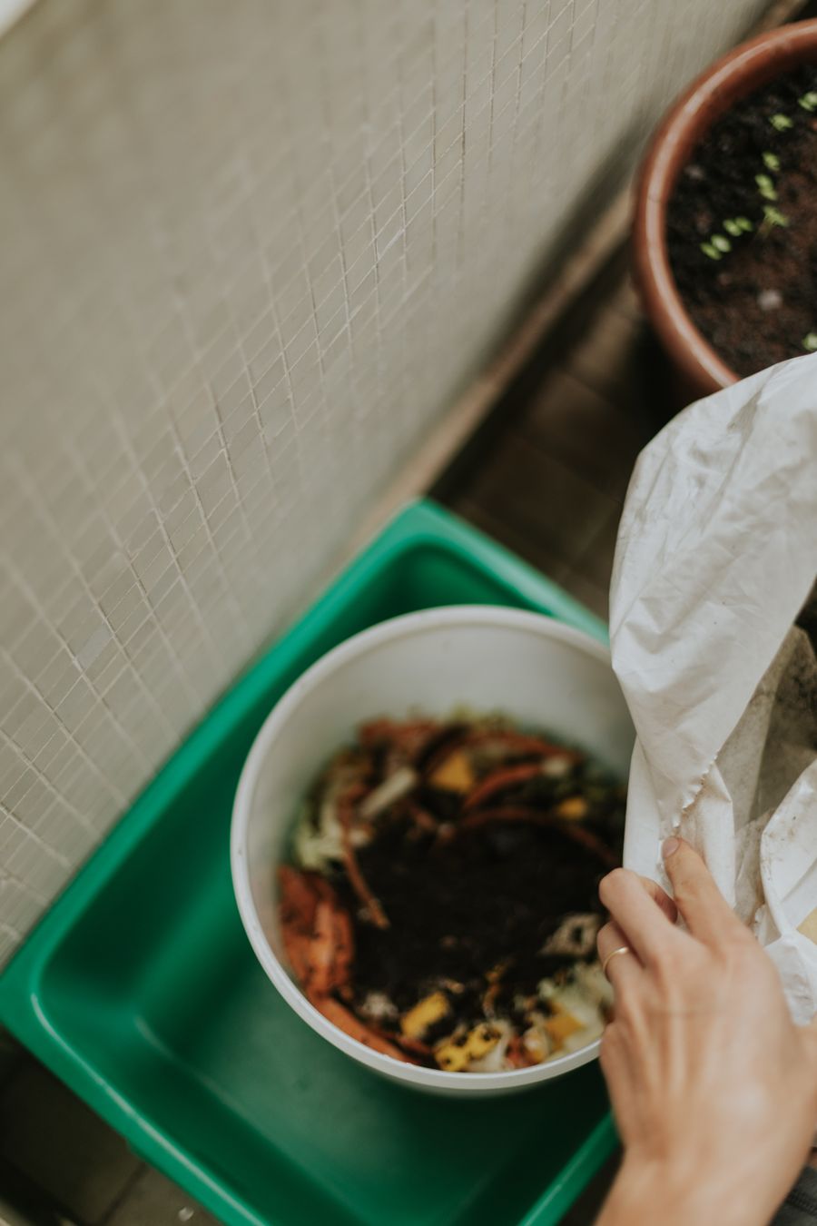 Hands adding kitchen scraps to a home compost bowl