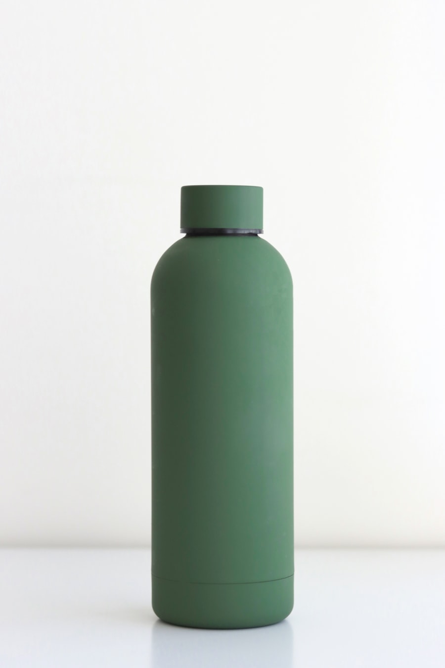Matte green stainless steel water bottle on a white table