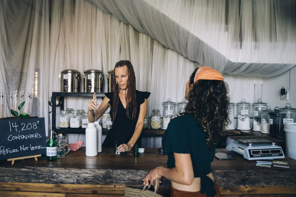 Two shop staff chatting at the wooden refill counter
