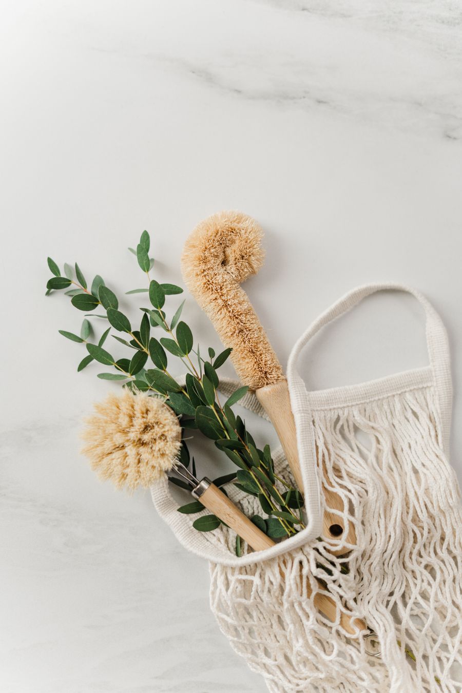 White knit bag holding wooden cleaning brushes