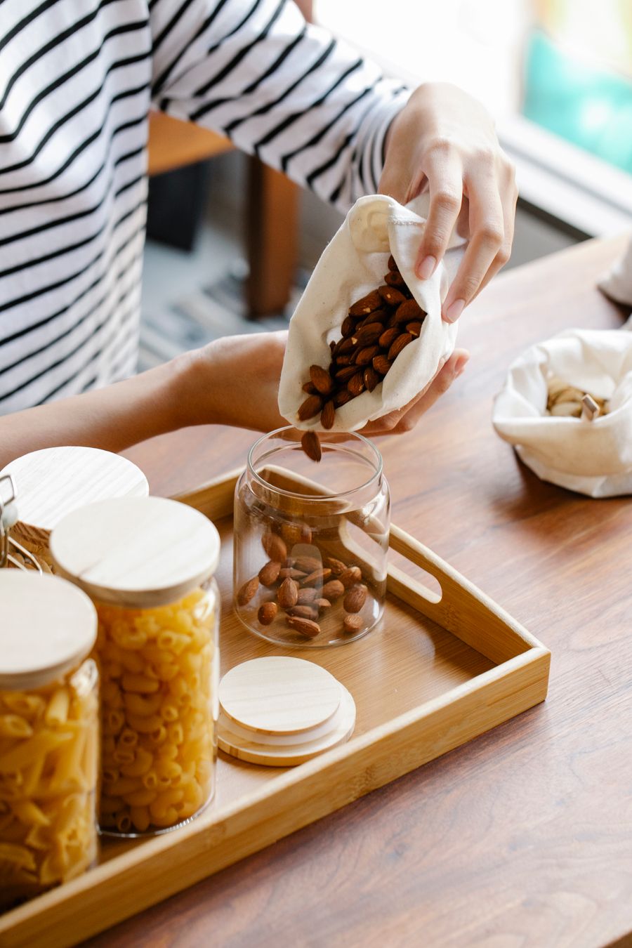 Woman pouring almonds into a glass jar at a refill station
