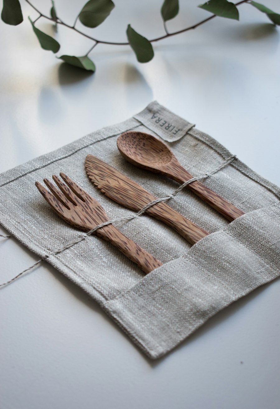 Wooden fork, spoon and knife resting on linen